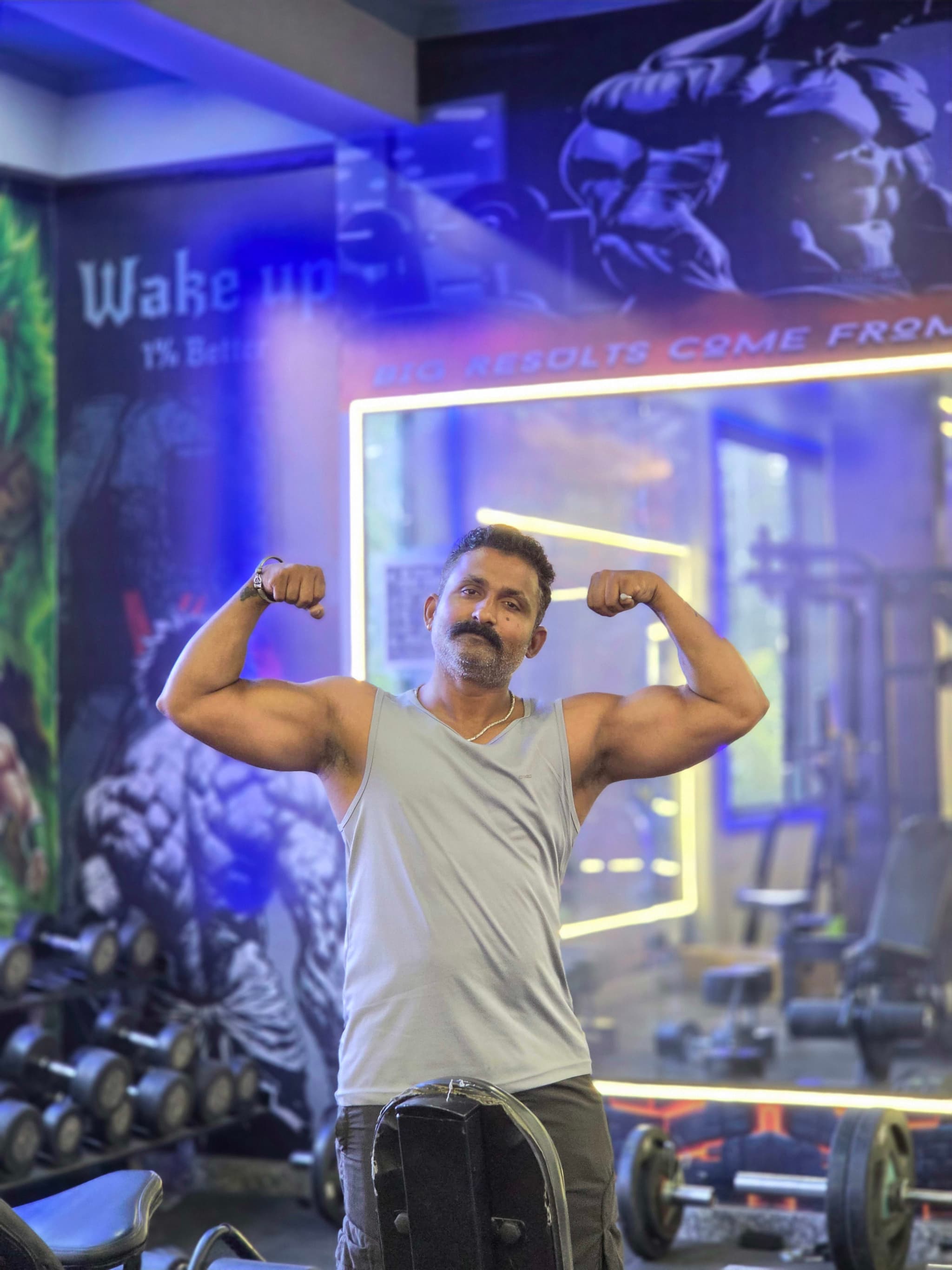 Trainer flexing his bicep on the G2 Fitness Club training floor
